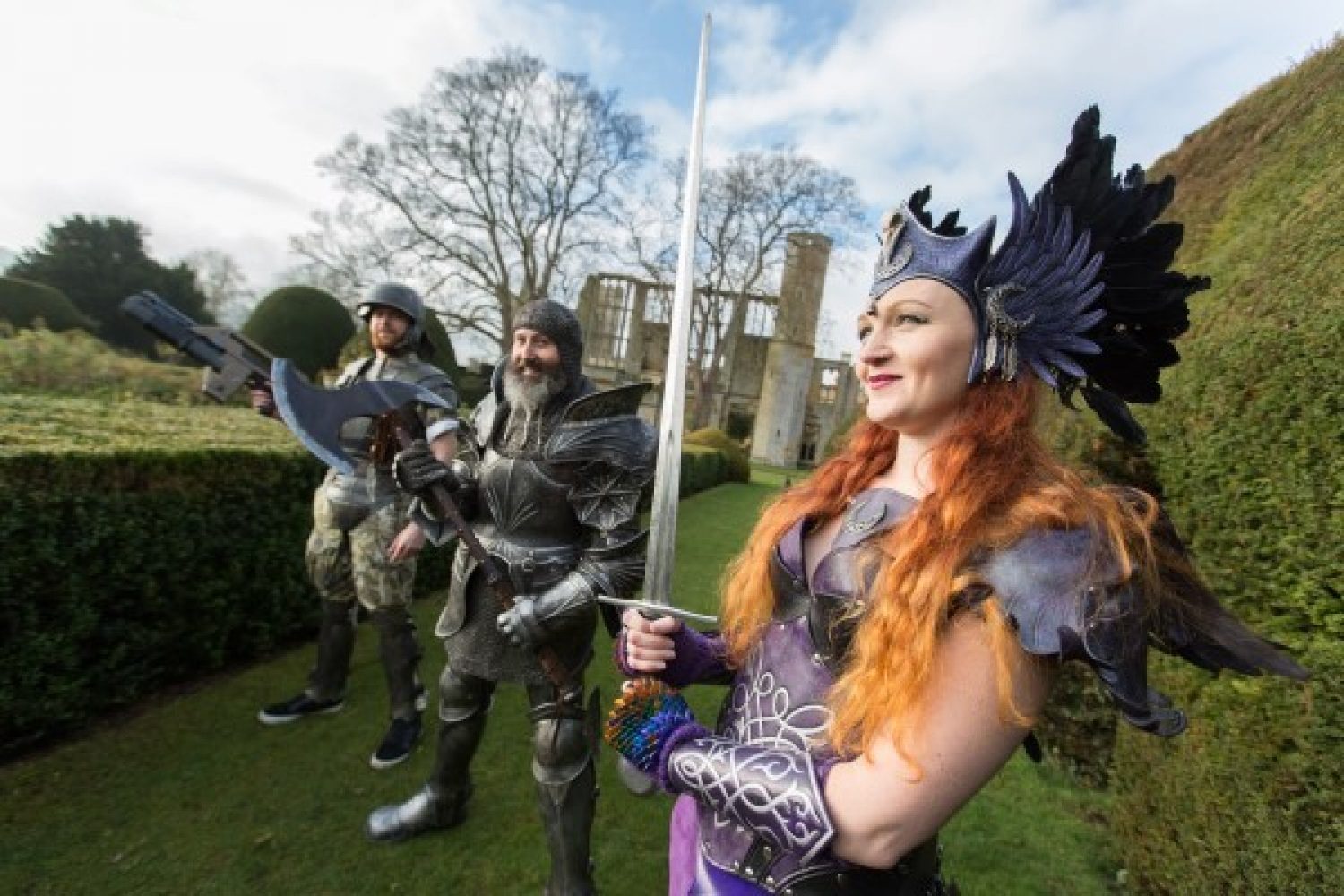 3 performers in medieval armour hold their weapons aloft