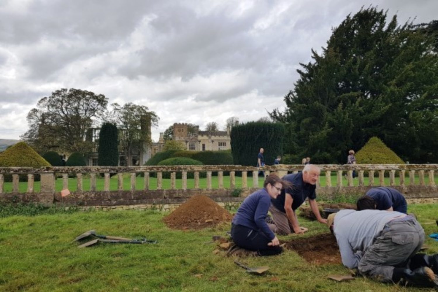 Archaeologists kneeling around dig site in the grounds of the castle